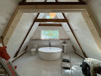 a bathroom in an attic with wooden beams and a bathtub