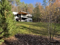 a modern house sits on top of a hill in the woods